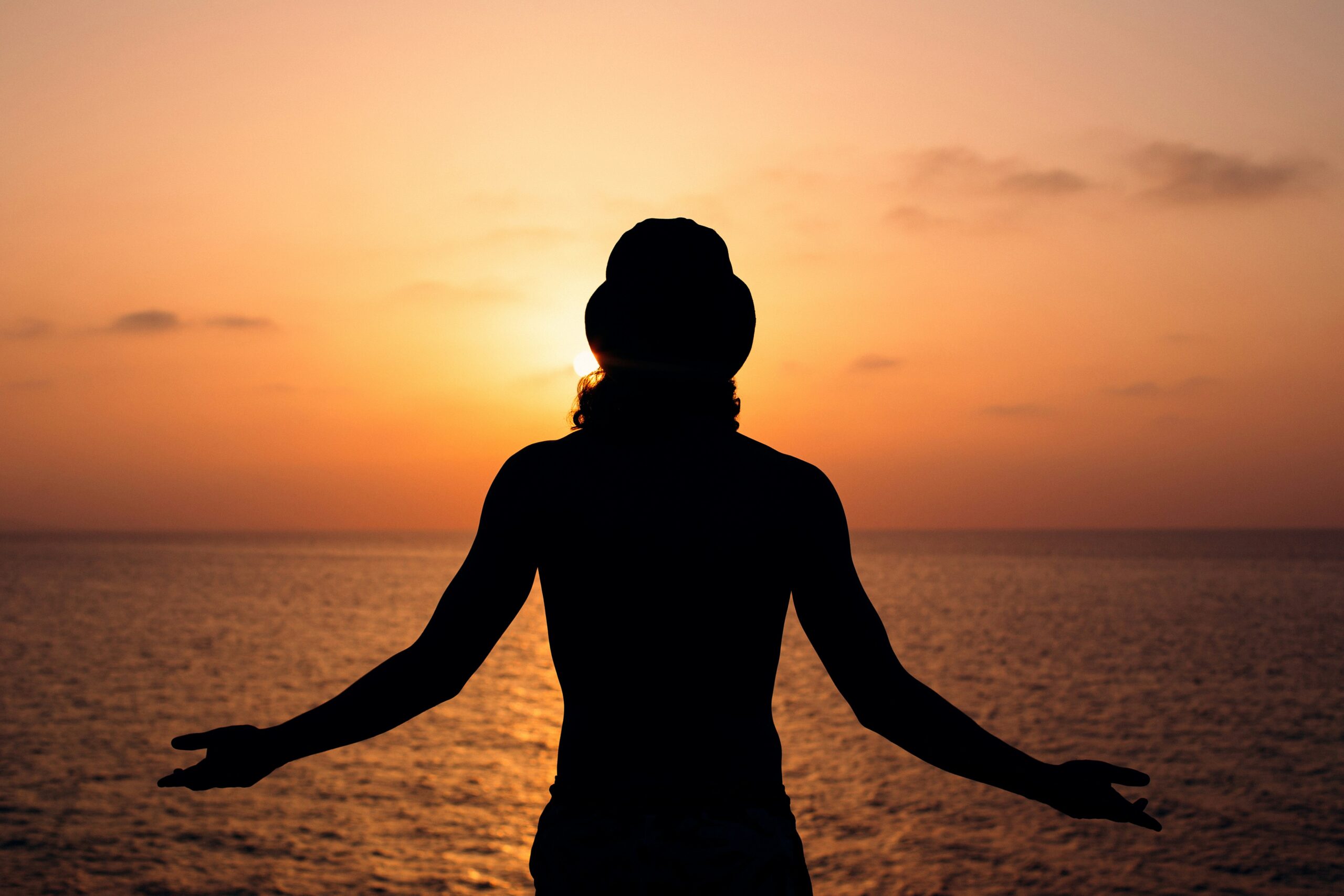 Mulher de braços abertos ao pôr do sol representando poder e liberdade feminina