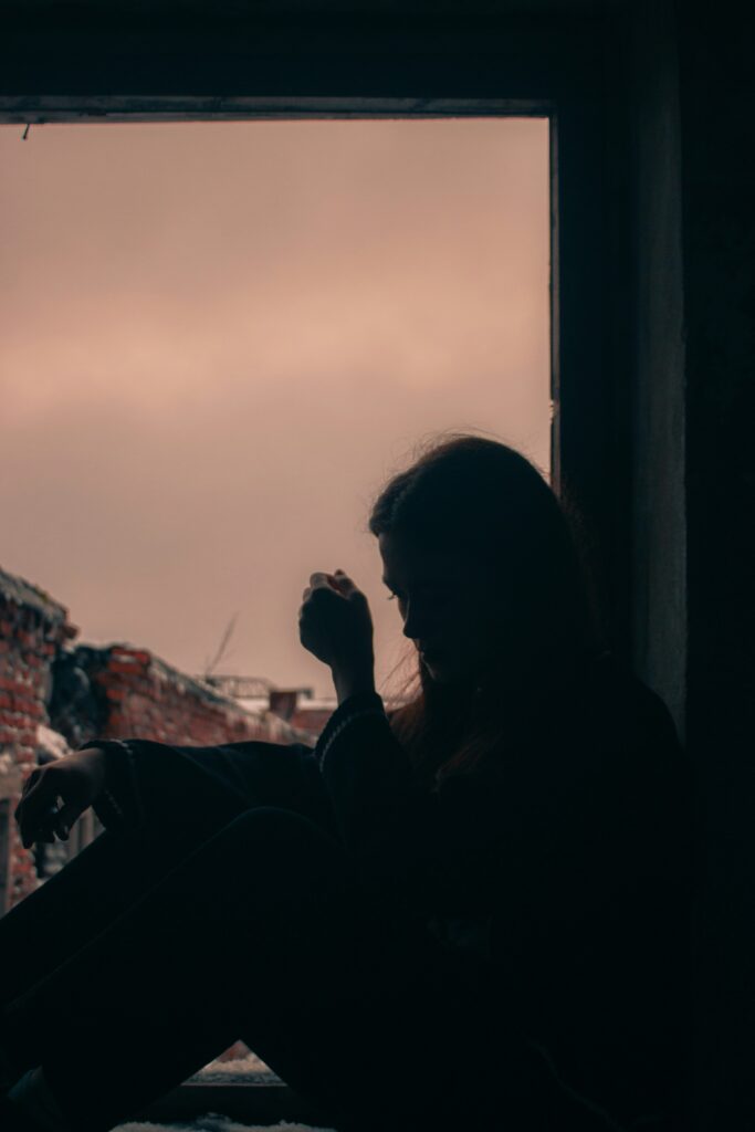 mulher pensativa olhando pela janela, representando sinais de relacionamento abusivo