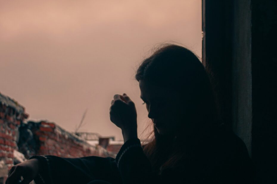 mulher pensativa olhando pela janela, representando sinais de relacionamento abusivo